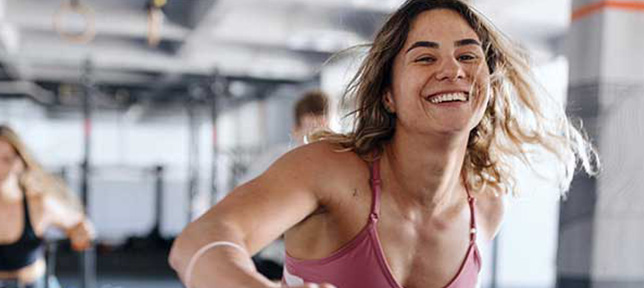 Chica haciendo deporte en sala fitness sonriente