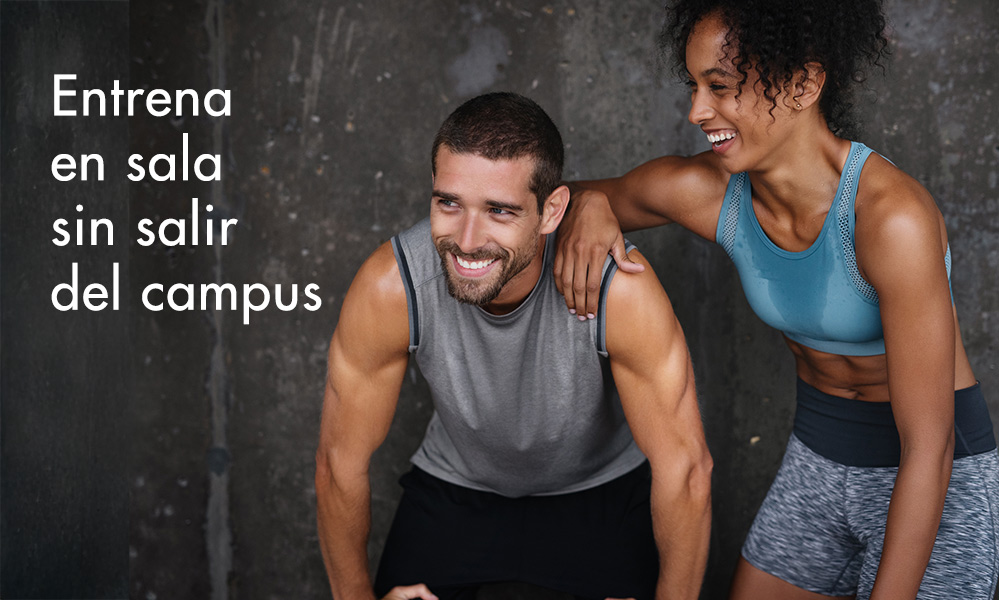 Dos personas sonrientes, un hombre y una mujer, se toman un descanso en un gimnasio. El hombre lleva una camiseta sin mangas gris y la mujer un top deportivo turquesa. Texto: