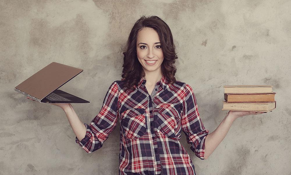 chica con un ordenador en una mano y en la otra libros