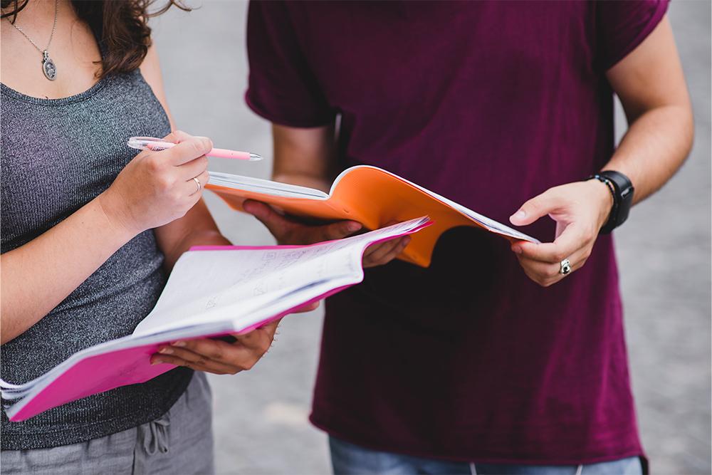 Dos estudiantes comparando apuntes en sus cuadernos