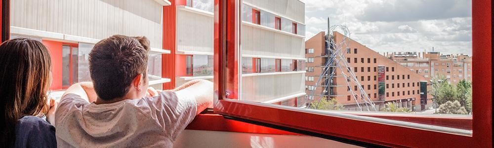 Un chico y una chica mirando por la ventana de la residencia Peces-Barba