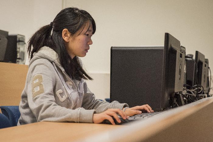 Alumna sentada frente a ordenador en Universidad Carlos III de Madrid