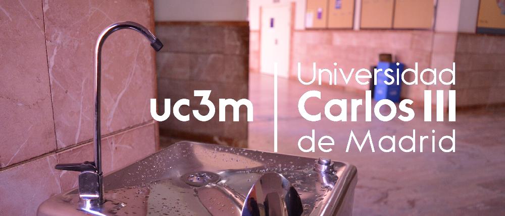 A la izquierda se ve una fuente de agua de la universidad y a la derecha, el logo de la Universidad Carlos III de Madrid