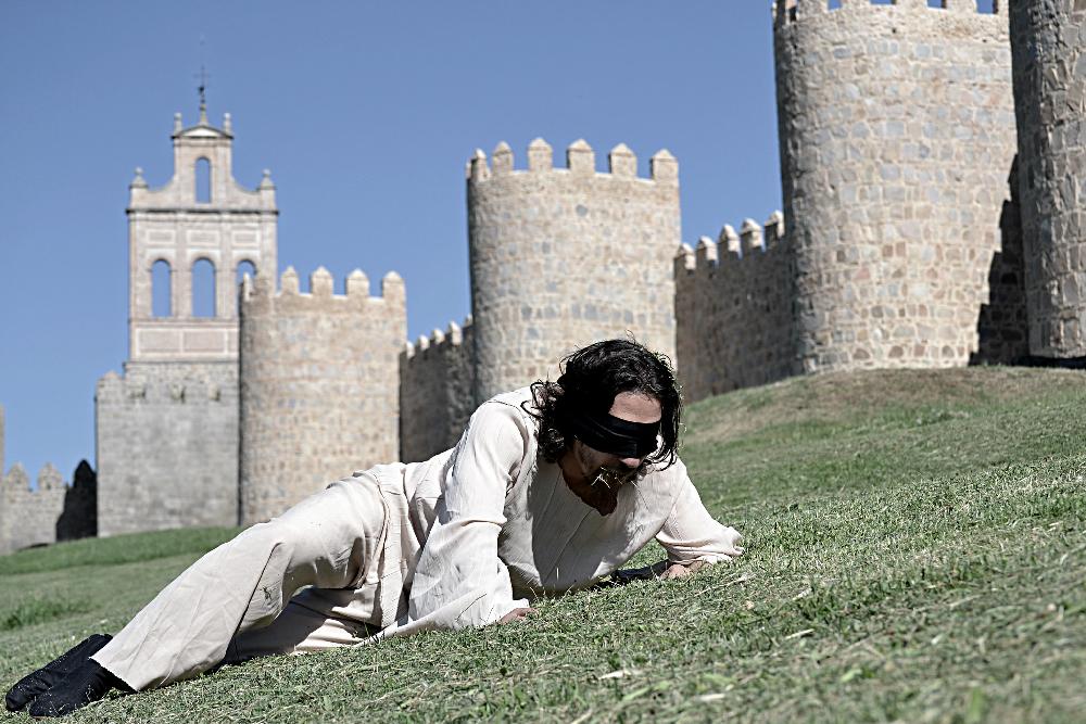 Hombre en la hierba junto a muralla medieval
