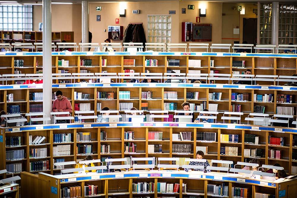 Personas sentadas en una biblioteca estudiando