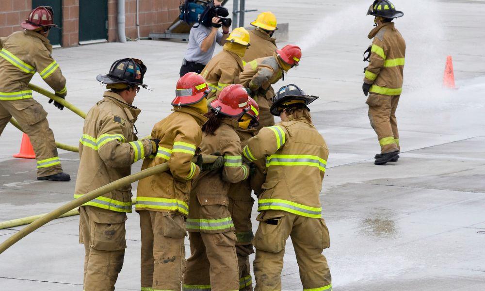 Equipo de bomberos y bomberas entrenando en un simulacro de incendio con una manguera. Crédito: UC3M