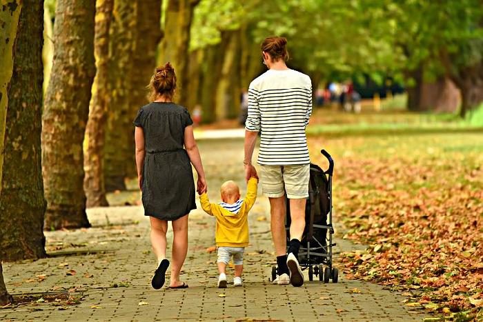 pareja paseando por el parque con un niño  