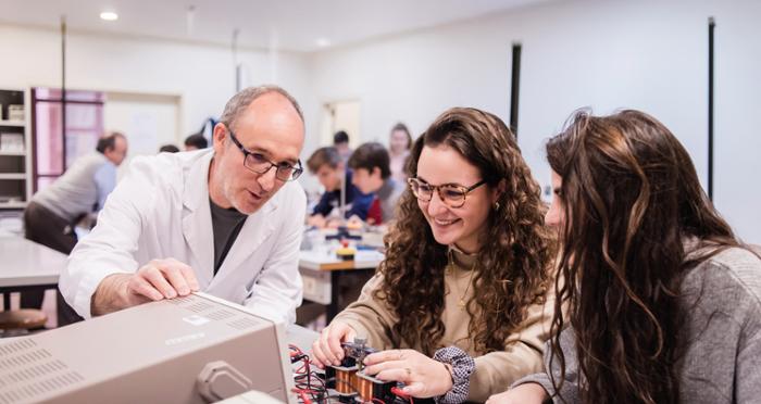 Un profesor trabaja con dos alumnas en un laboratorio tecnológico